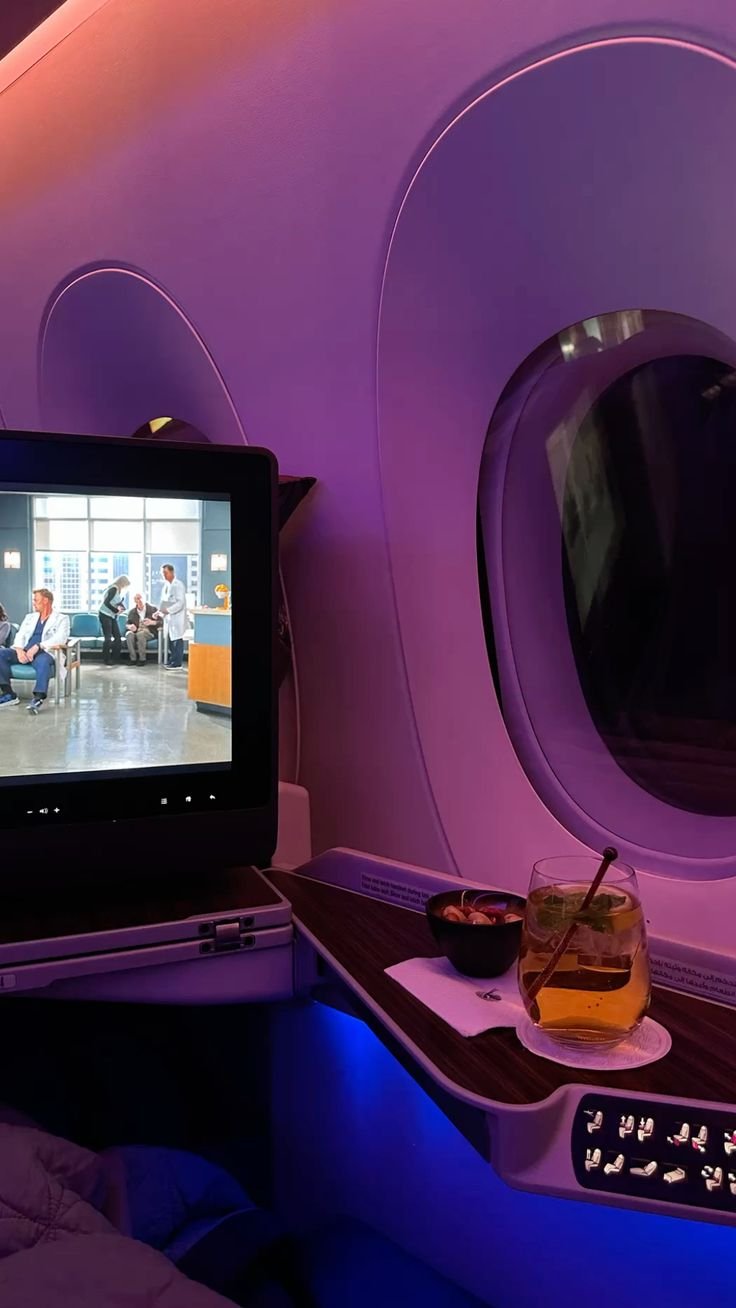 Violet lit business class suite with a drink served by the window
